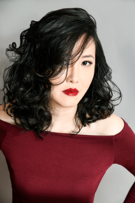 author photo, black curly haired woman wearing red short and red lipstick